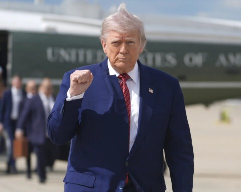 Donald Trump walks away from helicopter with fist raised and wind-blown hair