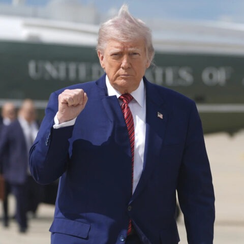 Donald Trump walks away from helicopter with fist raised and wind-blown hair