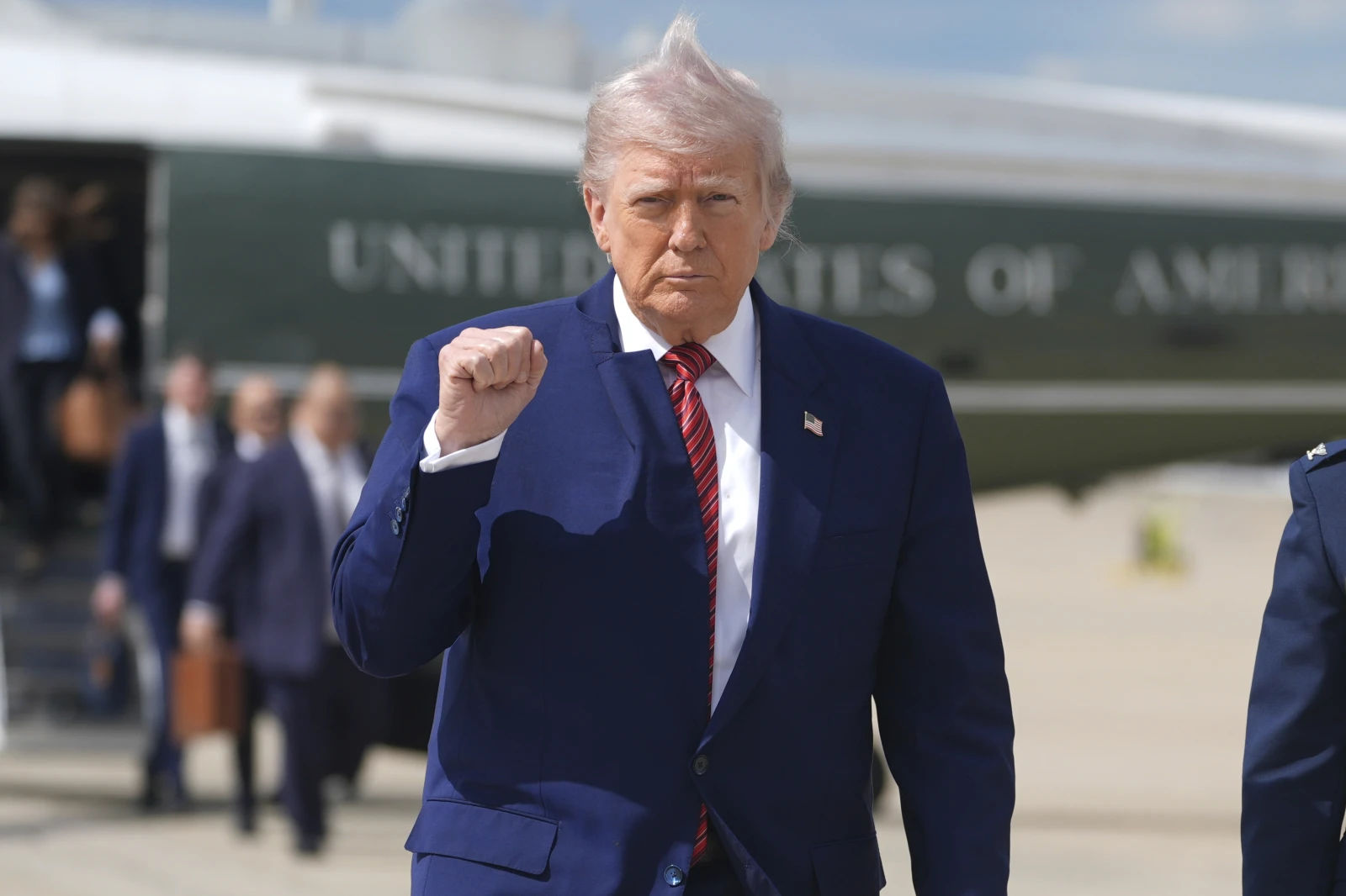 Donald Trump walks away from helicopter with fist raised and wind-blown hair