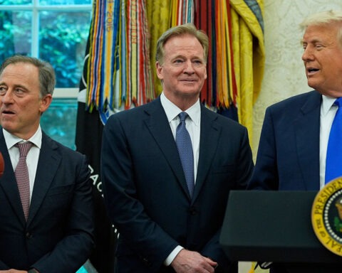 Trump in suit awkwardly holding a sports medal