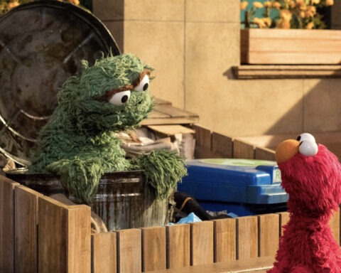 Oscar the Grouch and Elmo speaking outside a trash can
