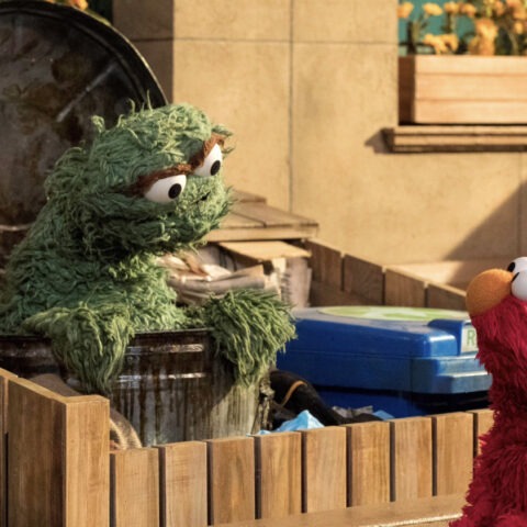 Oscar the Grouch and Elmo speaking outside a trash can