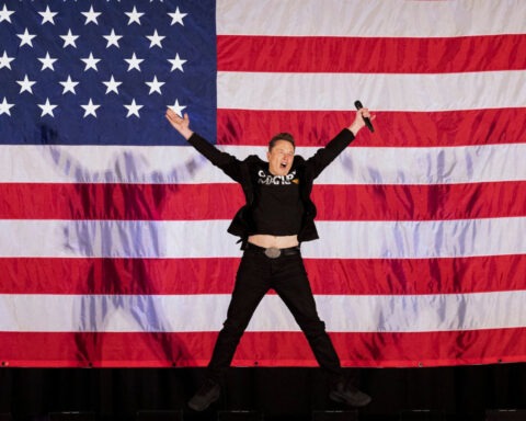 Elon Musk jumping in front of American flag during America Party launch
