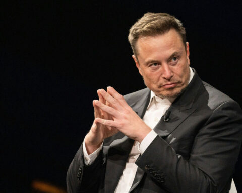 Elon Musk sitting with fingers steepled, plotting something strange