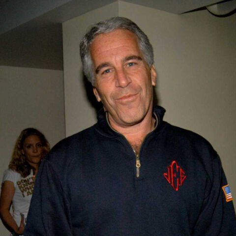 Man in dark zip-up sweater believed to be Jeffrey Epstein smirking at camera