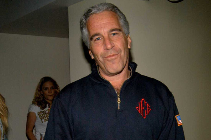 Man in dark zip-up sweater believed to be Jeffrey Epstein smirking at camera