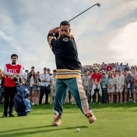 Adam Sandler mid-swing as Happy Gilmore on a crowded golf course