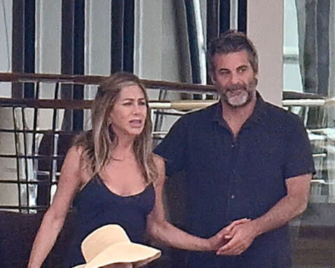 Jennifer Aniston and Jim Curtis holding hands aboard a luxury yacht