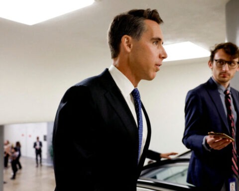 Senator Josh Hawley speaking to a reporter in a government hallway