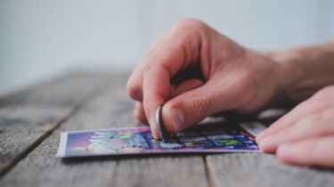 Close-up of man scratching off lottery ticket with a coin