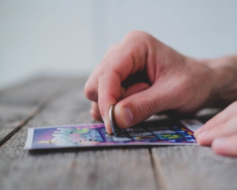 Close-up of man scratching off lottery ticket with a coin