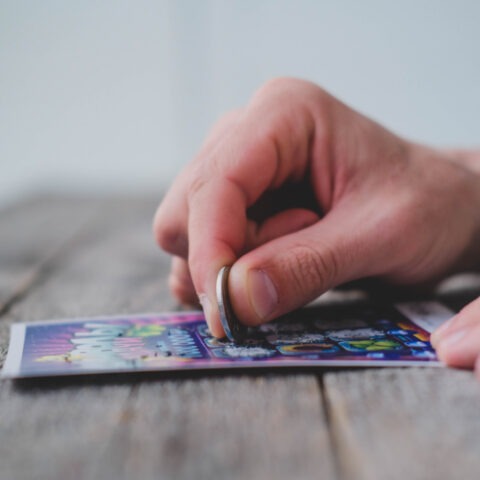 Close-up of man scratching off lottery ticket with a coin