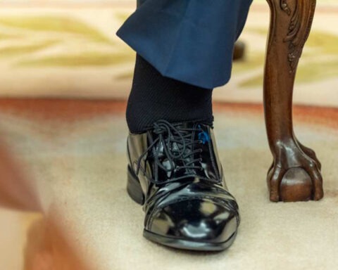 Close‑up of Trump’s polished black shoe and leg while seated