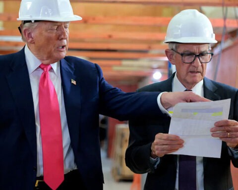 Trump and Jerome Powell wearing hard hats and reviewing renovation blueprints during Federal Reserve site visit