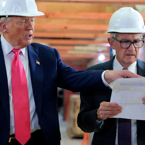 Trump and Jerome Powell wearing hard hats and reviewing renovation blueprints during Federal Reserve site visit
