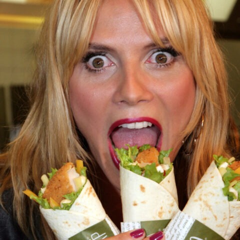 Woman with shocked expression holding three McDonald’s Snack Wraps near her open mouth
