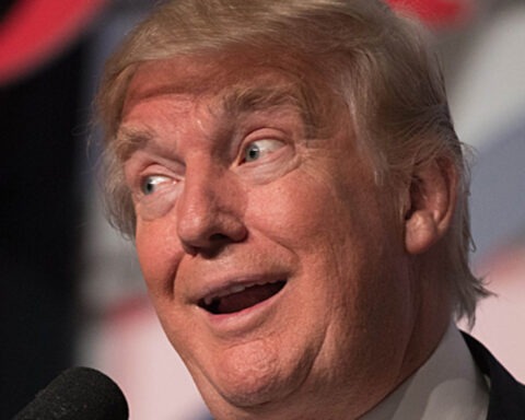 Donald Trump making a dumb facial expression at a microphone