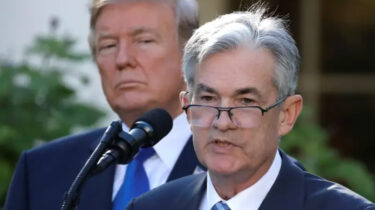 Donald Trump glares behind Jerome Powell during a press conference