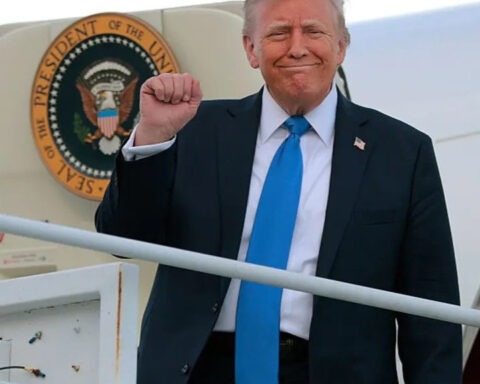 Donald Trump smiles and raises his fist while stepping off Air Force One