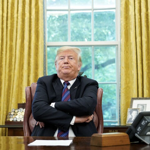 Donald Trump sits with arms crossed at Oval Office desk