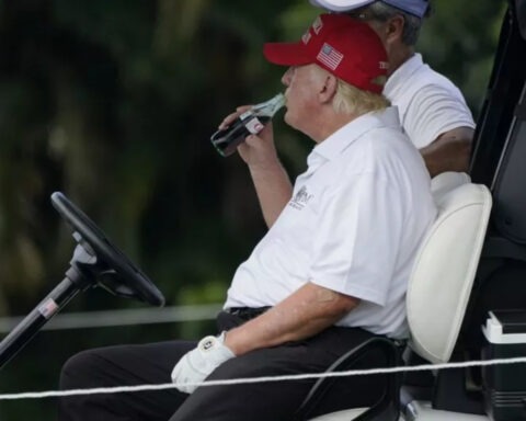 Donald Trump drinking Coca-Cola in a golf cart