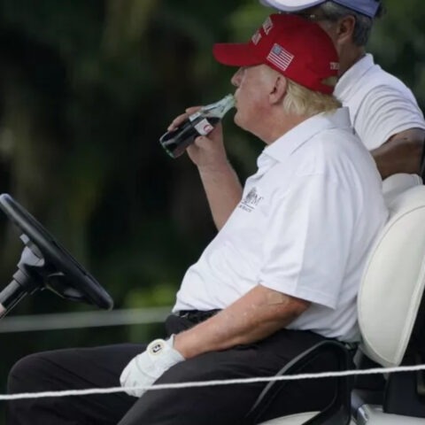 Donald Trump drinking Coca-Cola in a golf cart