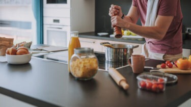 Man cooking pasta in kitchen with groceries on counter