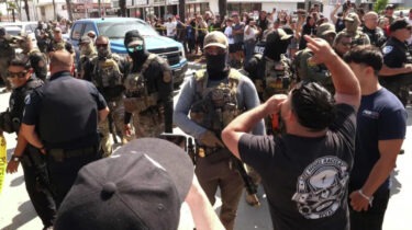 ICE agents in tactical gear surrounded by protesters during Los Angeles workplace raid