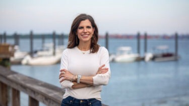 Nancy Mace stands near a dock smiling with arms crossed