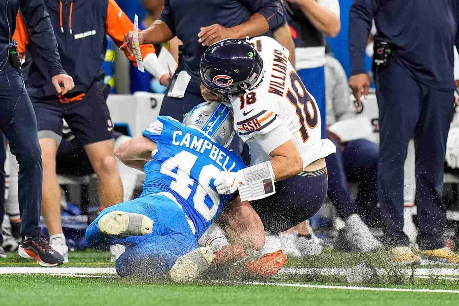 Chicago Bears quarterback Caleb Williams tackled by Detroit Lions defender during NFL game.