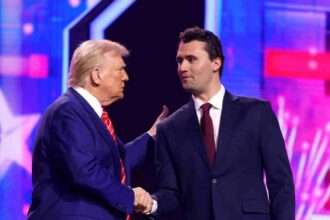 Donald Trump shaking hands with Charlie Kirk on stage