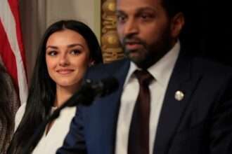 FBI Director Kash Patel speaks at an event as Alexis Wilkins looks on