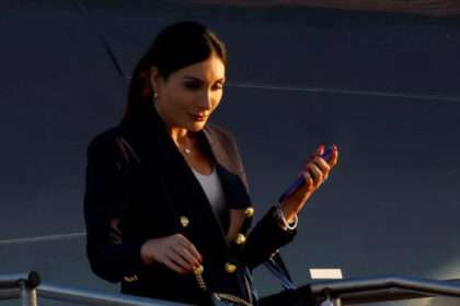 Laura Loomer descending airplane stairs while holding a phone.