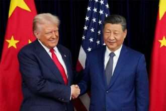 President Donald Trump shakes hands with Chinese President Xi Jinping in front of U.S. and Chinese flags.