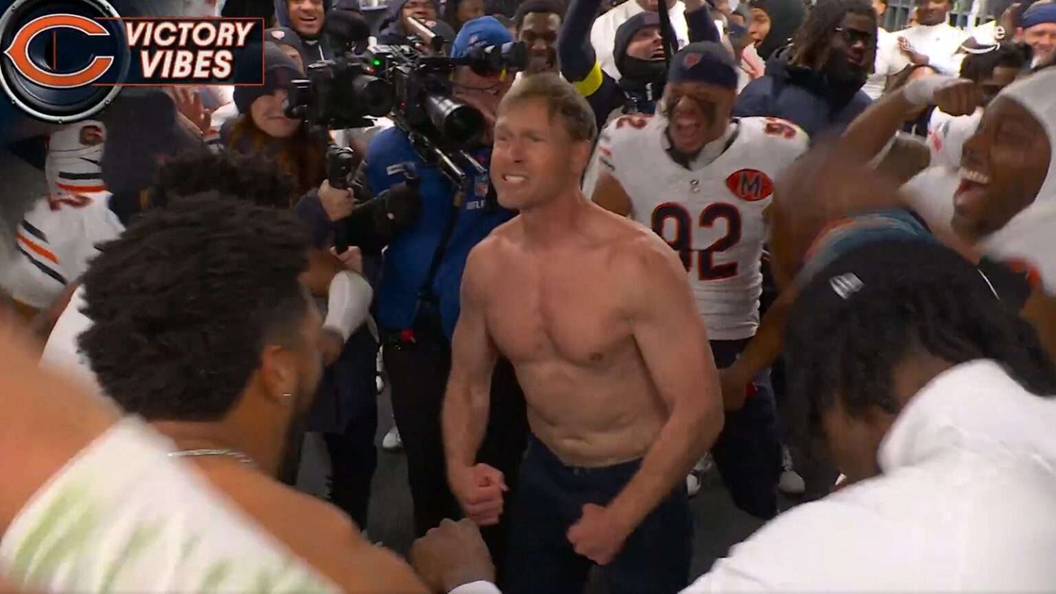 Chicago Bears head coach Ben Johnson celebrates shirtless in a crowded locker room after a win over the Philadelphia Eagles.