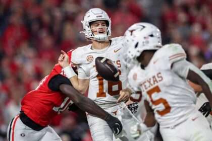 Texas quarterback Arch Manning is hit by a Georgia defender during a play, causing the ball to come loose.