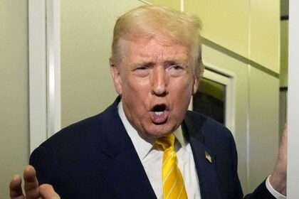 President Donald Trump speaking on an airplane while gesturing at reporters.