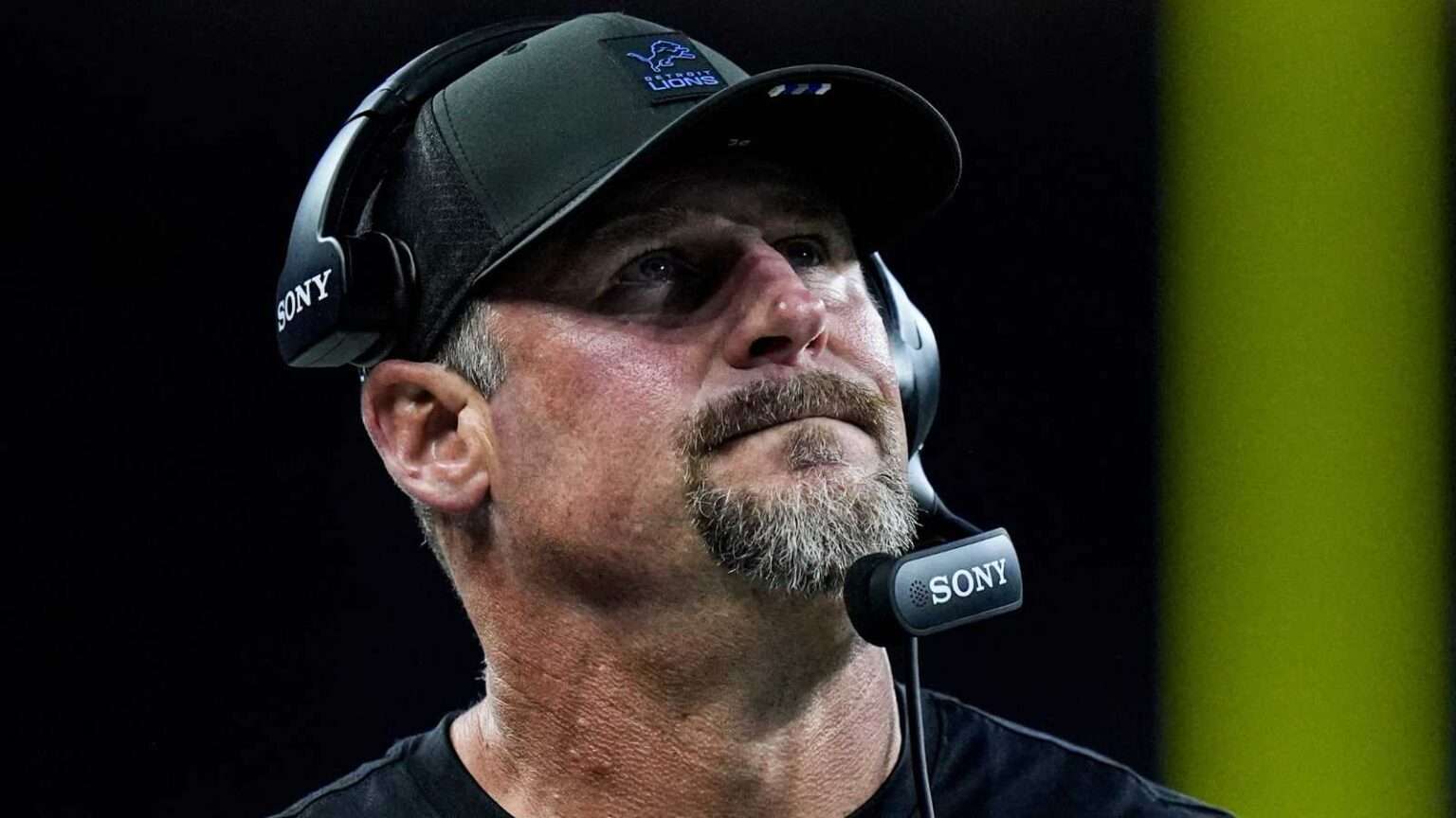 Detroit Lions head coach wearing a headset on the sideline during a game.